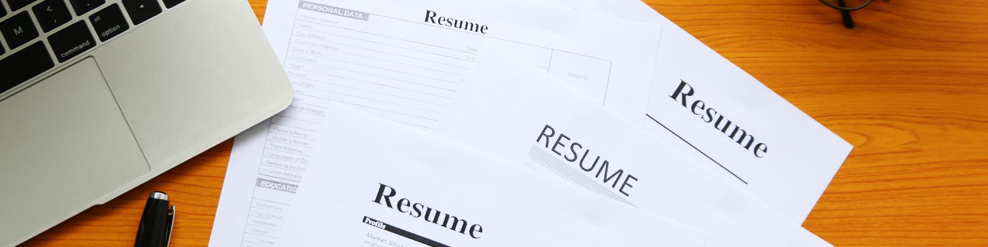 resumes on a table with a pen and laptop